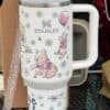 Decorative insulated travel mug with cute bear and flower design, Stanley logo.