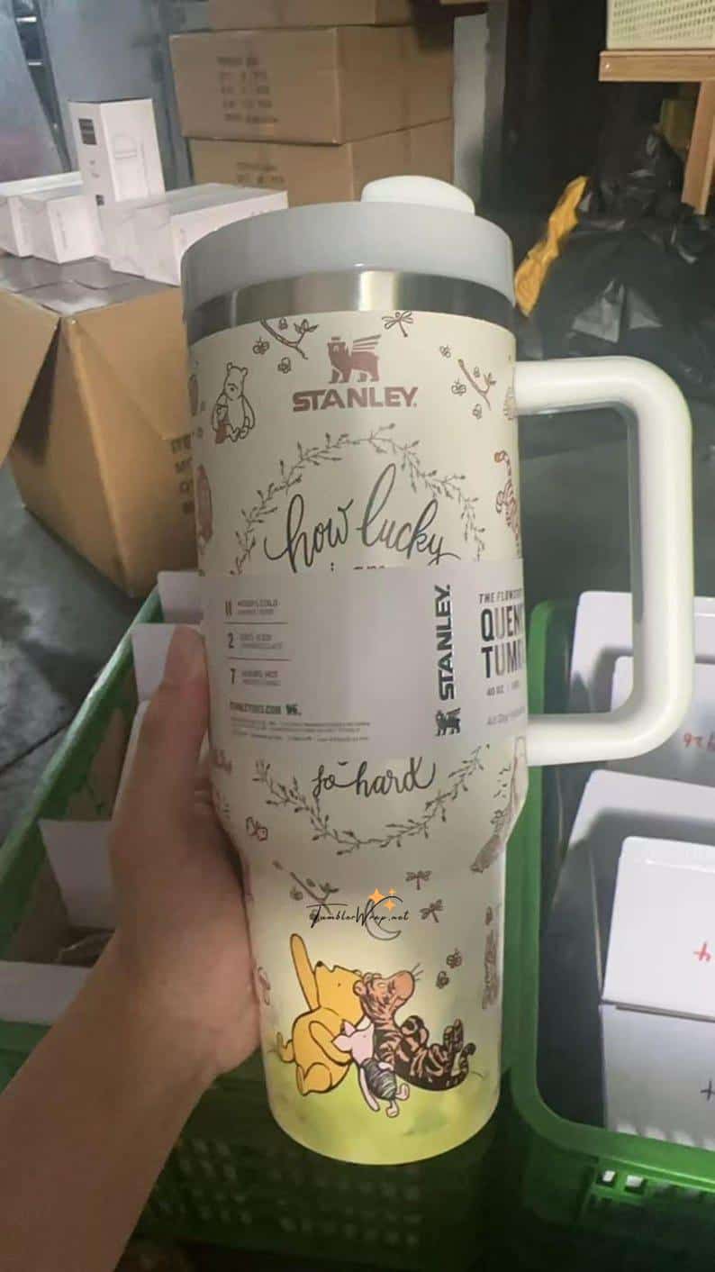 A Stanley tumbler with Winnie the Pooh and friends, promoting luck and happiness.