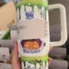 Halloween mug with pumpkin, spider webs, and monster designs for Halloween fun.
