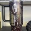 Dark-themed coffee tumbler with spooky ghost and horror mask illustrations.