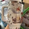 Adorable Winnie the Pooh illustration on a white insulated travel mug with floral design.