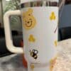 Cute Winnie the Pooh with honeycomb design, bee, and honey dipper.