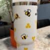 Colorful bee and honeycomb travel mug design.