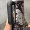 Close-up of a themed coffee mug featuring horror movie icons, held in hand.