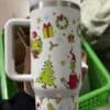 Festive holiday mug featuring Christmas trees, Santa, wreaths, and gifts.
