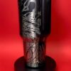 Travel mug with abstract black and white design on red background.
