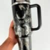 Black travel mug with dragon and skull designs.