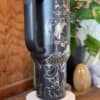 Metal travel mug with demon and skull illustration, ideal for gothic or alternative decor.